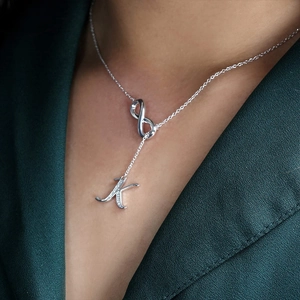 Silver infinity necklace with sparkling zircon letter K pendant on a woman wearing green