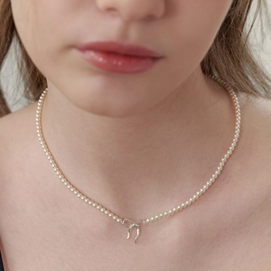 Collier en perles style français avec pendentif nœud argenté porté par un modèle
