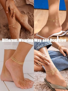 Detail of layered gold cuban ankle bracelets with K and M initial pendants on foot