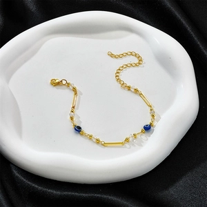 Eleganteres goldenes Evil Eye Armband mit blauen Perlen auf schwarzem Seidenhintergrund