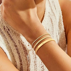 Set di tre gioielli dorati con bracciale rigido inciso K e catene raffinate in acciaio inox