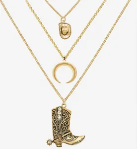 Dettaglio ravvicinato di una collana a tre strati placcata oro con ciondolo a stivale cowboy