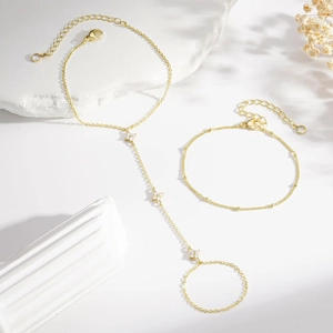 Elegant gold clover finger bracelet with zircon stones on a white decorative background