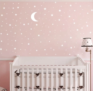 Star and moon wall stickers displayed on a pink wall above a white baby crib