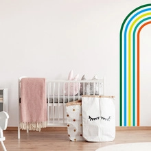 Détail d'un sticker mural arc-en-ciel coloré dans une chambre de bébé chaleureuse