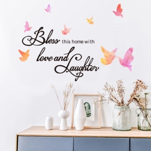 Détail du sticker mural avec oiseaux colorés et citation Bless this home with love and laughter