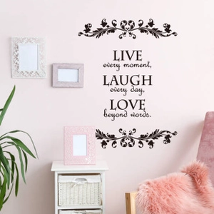 Stickers muraux inspirants Live Laugh Love avec motifs floraux sur un mur de chambre rose