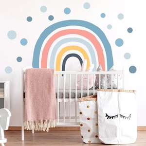 Stickers muraux arc-en-ciel et pois bleus au-dessus d'un berceau dans une chambre