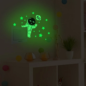 Luminous wall stickers featuring astronauts and stars glowing in a dark room environment