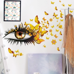 Détail de stickers muraux avec yeux artistiques et papillons dorés dans un salon
