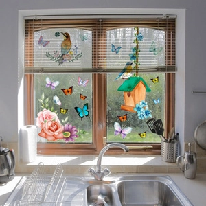 Detailed view of floral and butterfly static window stickers on a bright kitchen glass pane