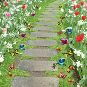 Detailed view of colorful 3D butterfly garden stakes placed among tulips along a path
