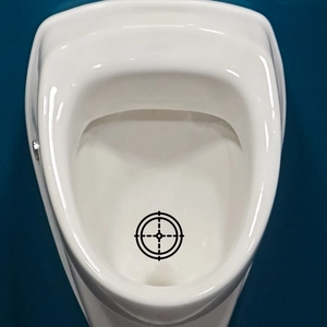 Detail view of a round black urinal target sticker inside a white ceramic urinal bowl