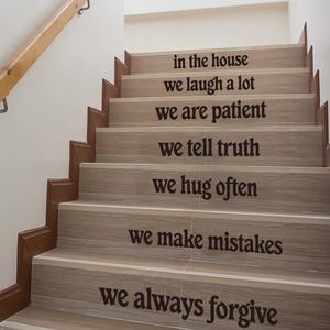 Close-up of minimalist black vinyl letter stickers with family quotes on wooden stairs