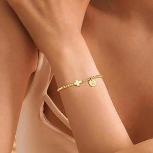 Goldenes Perlenarmband aus Edelstahl mit Kreuz und K-Anhänger am Handgelenk einer Frau