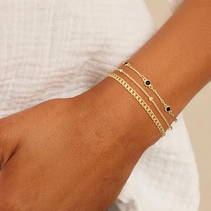 Three-piece layered gold bracelet set featuring heart charms and black onyx accents