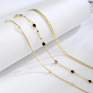 Three-piece gold layered bracelet set featuring box chain, black beads, and curb link