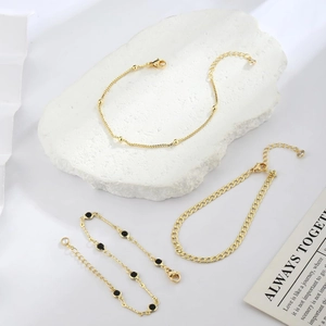 Three-piece gold layered bracelet set featuring bead chain, curb links and black disc charm