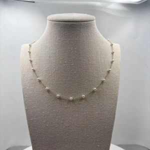Elegant gold chain necklace featuring small white pearls on a display stand
