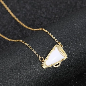 Collana megafono dorata con pendente in smalto bianco su sfondo nero ruvido