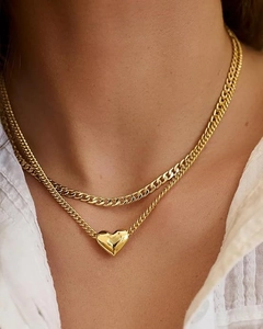 Détail de colliers dorés superposés avec pendentif cœur poli et maille gourmette