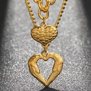 Layered gold necklace featuring textured solid heart and hollow wing-heart pendant