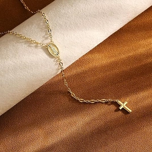 Detailed shot of golden rosary style necklace with cross pendant and Mary medal
