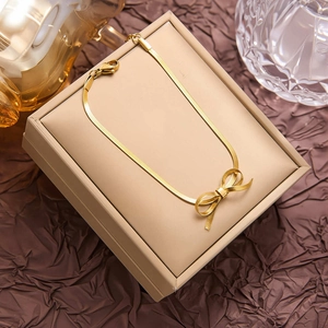 Elegante collana placcata oro 18K con ciondolo a fiocco esposta su portagioie