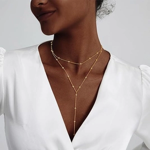 Collana a doppio strato con perline dorate e catena a nappa a Y su modella elegante