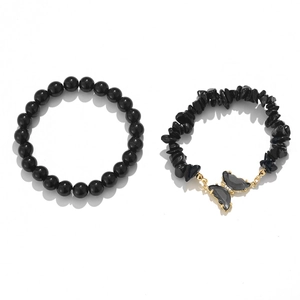 Detailed macro view of black natural stone beads and gold butterfly pendant bracelet