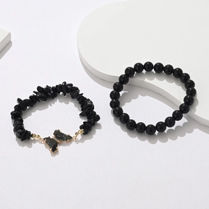 Detail of black natural stone beaded bracelets with a golden butterfly crystal pendant set