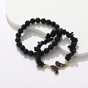 Macro detail of black natural stone bracelets set with a delicate butterfly charm