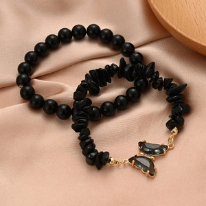 Detail view of two-piece black stone bracelets with a golden butterfly crystal pendant