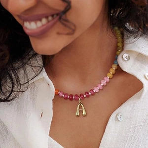 Collana di perline colorate con pendente a lettera A dorata indossata da modella