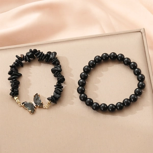 Detailed set of two black beaded bracelets featuring a butterfly charm on satin fabric