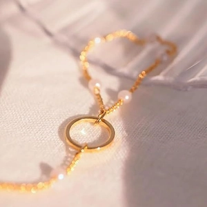 Squisito bracciale in oro 14k con perle bianche e un anello centrale dal design minimale