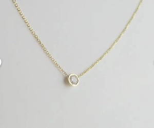 Detailed close-up of a delicate gold-plated clavicle chain with a bezel-set zircon pendant