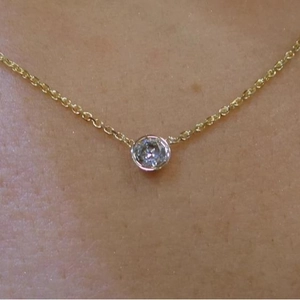 Minimalist gold necklace with bezel-set round crystal pendant shown on model neck