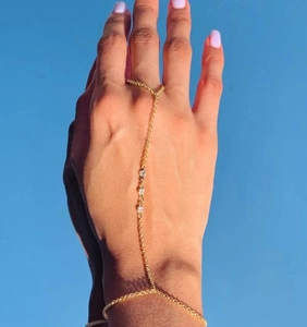 Detailed macro view of golden hand chain bracelet with three sparkling zircon crystals