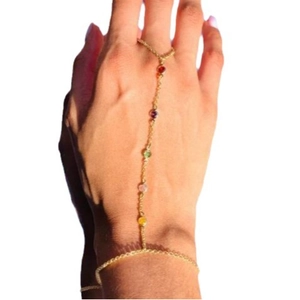 Gold slave bracelet with multi-colored gemstones and finger ring on a female model