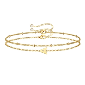 Dettaglio del bracciale dorato a strati con ciondolo lettera A e cristallo finale