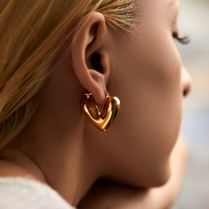 Chic 18K gold plated heart shaped earrings featuring a polished mirror finish on a model