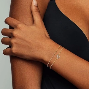 Layered gold beaded chain bracelet with a sparkling crystal letter M charm for women