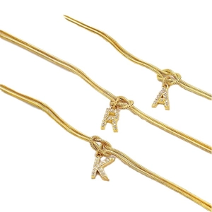 Gouden slangenschakel armbanden met zirkoon initialen A, R, K en knoop detail