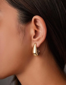 Detailansicht eines minimalistischen 14k Gold-Ohrrings in Tropfenform getragen von einem Model