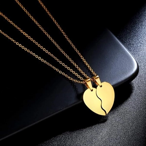 Polished gold stainless steel split heart couple necklace set on black display base