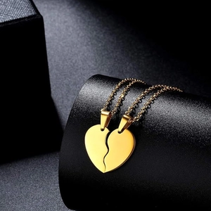 Polished gold stainless steel split heart couple necklace set on a luxury display stand