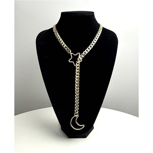 Dettaglio della collana a Y dorata a maglia cubana con ciondoli a stella e luna