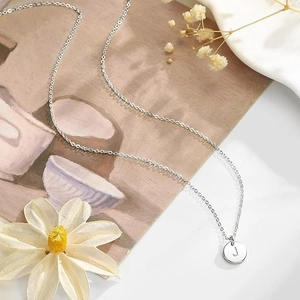Gros plan détaillé d'un collier pendentif pièce en argent gravé de la lettre J