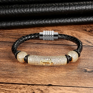 Detail of black woven leather bracelet featuring gold anchor clasp and sparkling crystals